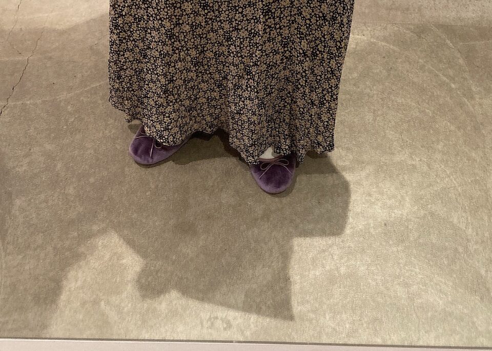 ブラックの小花柄のスカートにパープルのバレエシューズを履いた女性の足元