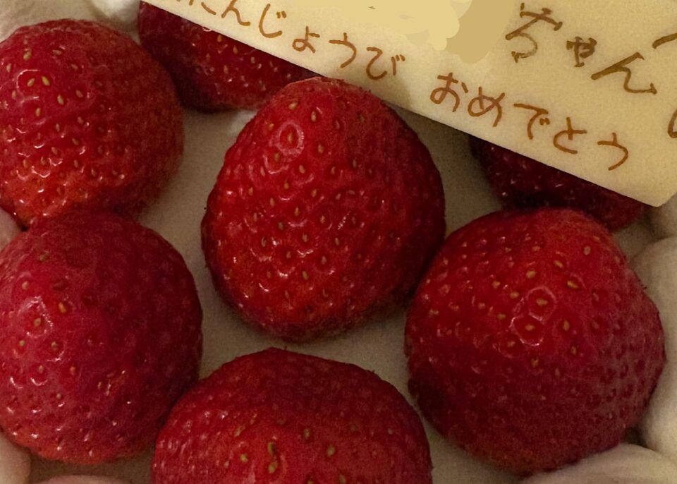 誕生日プレートがのせられたいちごのホールケーキ